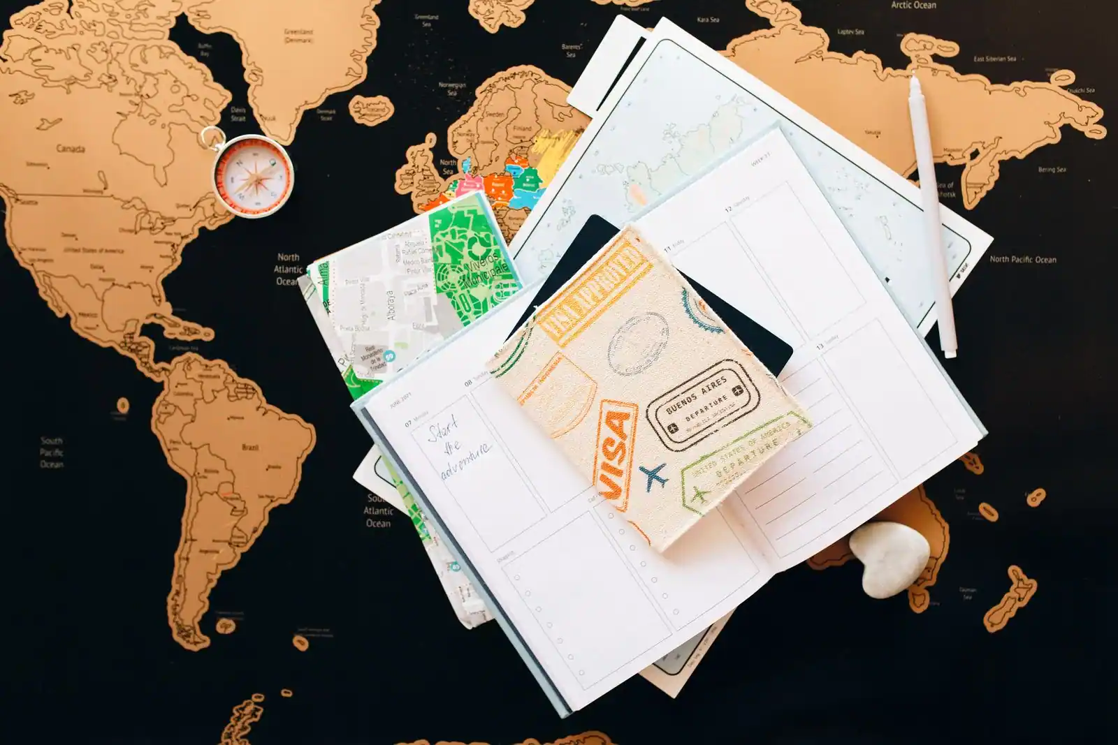 Passeport, carte dépliée et carnet posés sur une table pour préparer un voyage.