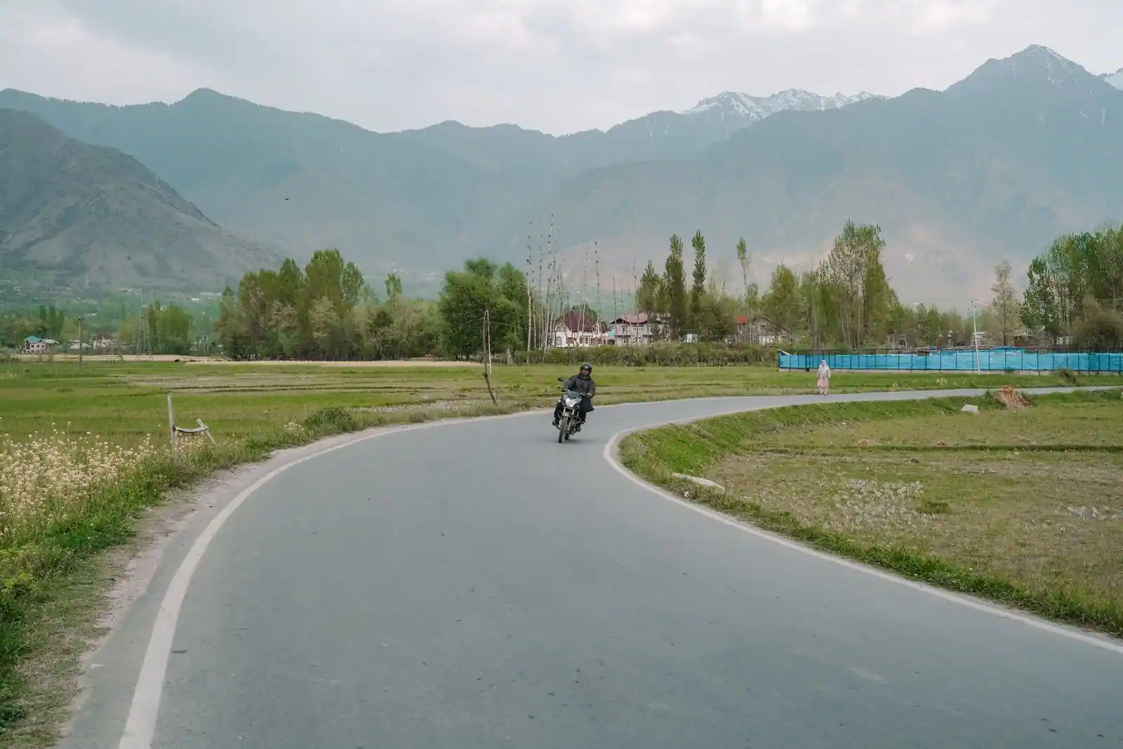 Motard roulant sur une route de campagne ouverte au pied des montagnes, illustration de l'actualité moto
