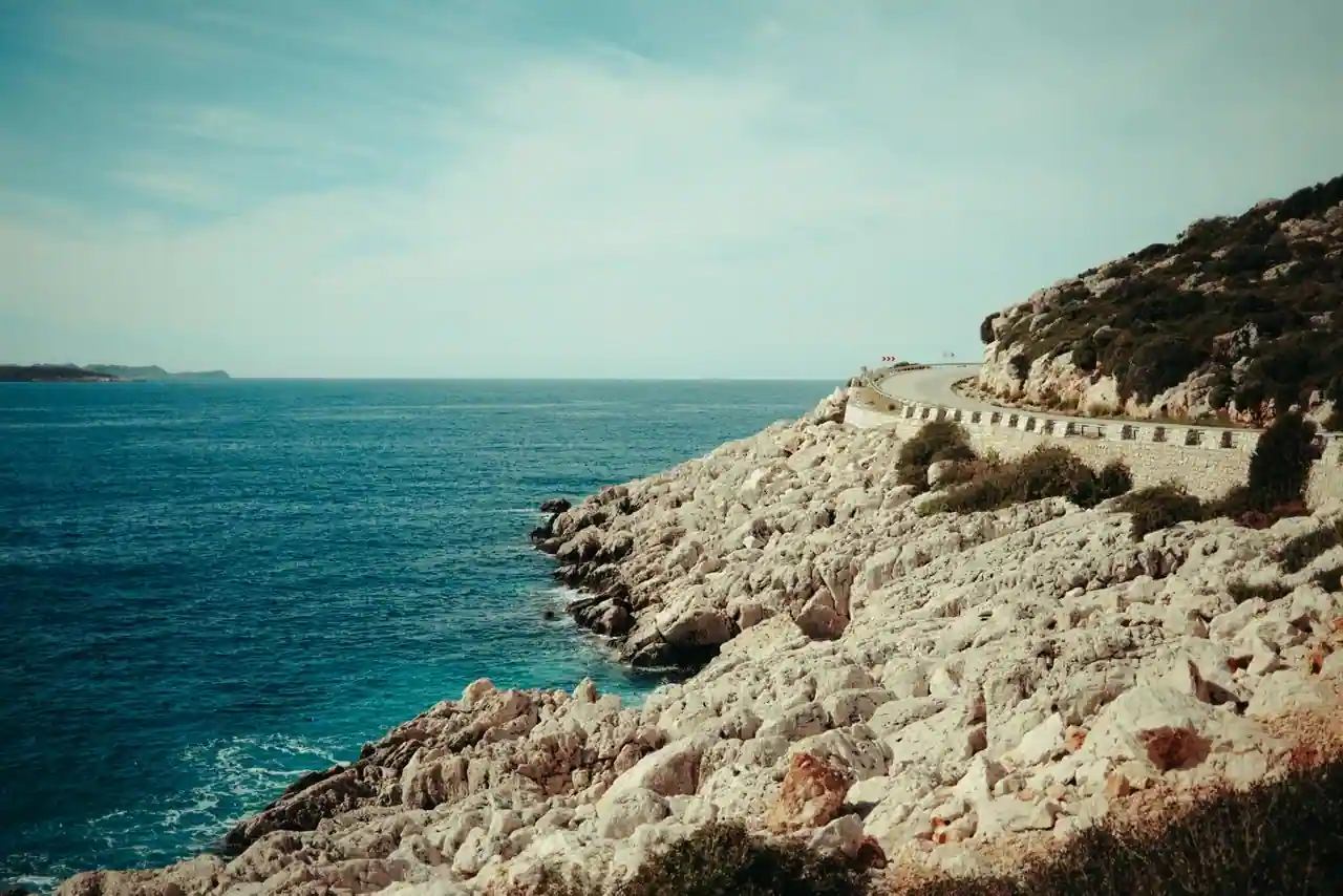Route panoramique longeant un littoral méditerranéen escarpé sous un ciel dégagé