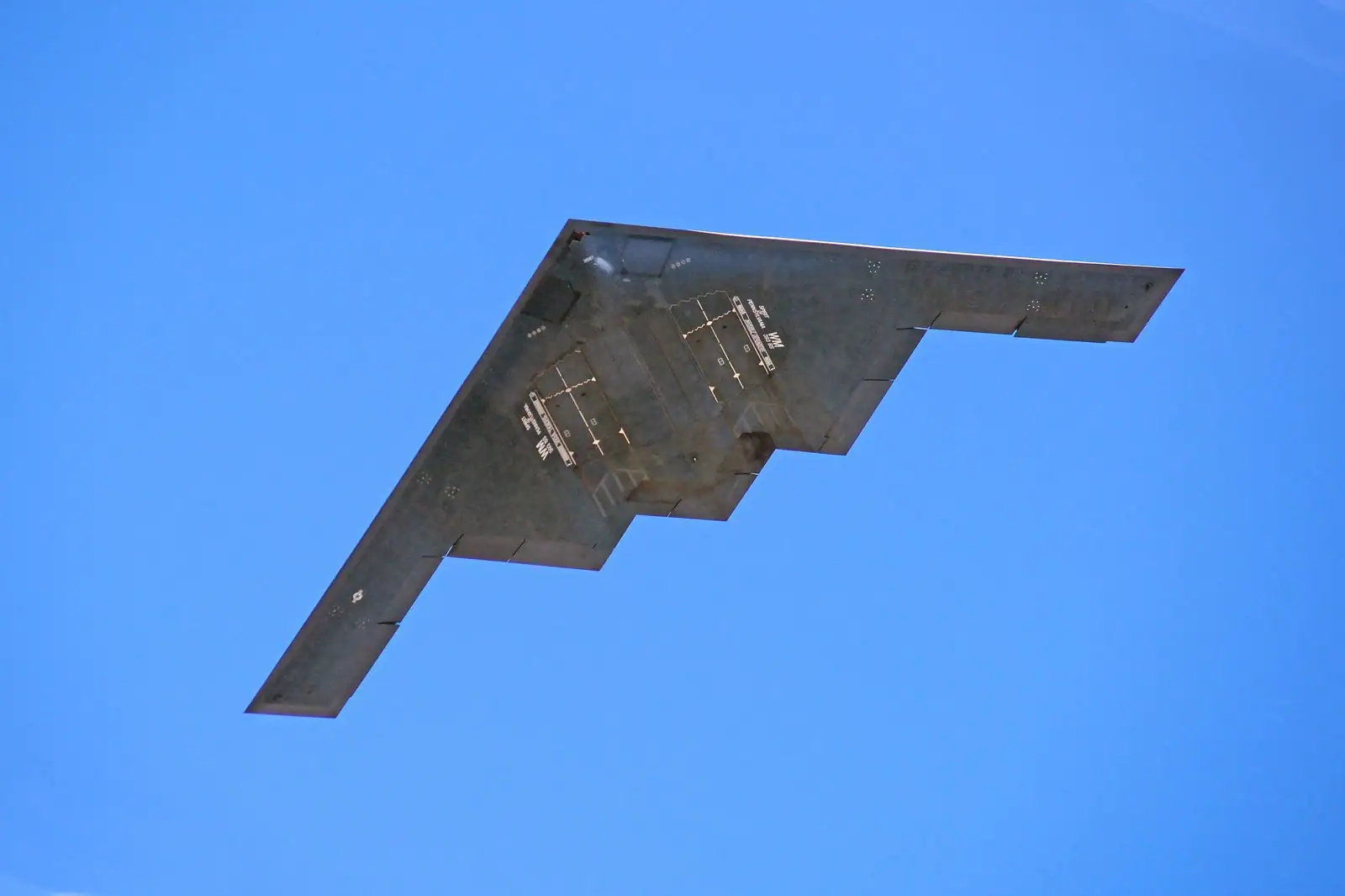 Bombardier furtif Northrop B-2 Spirit en vol, vu de dessous, contre un ciel bleu dégagé