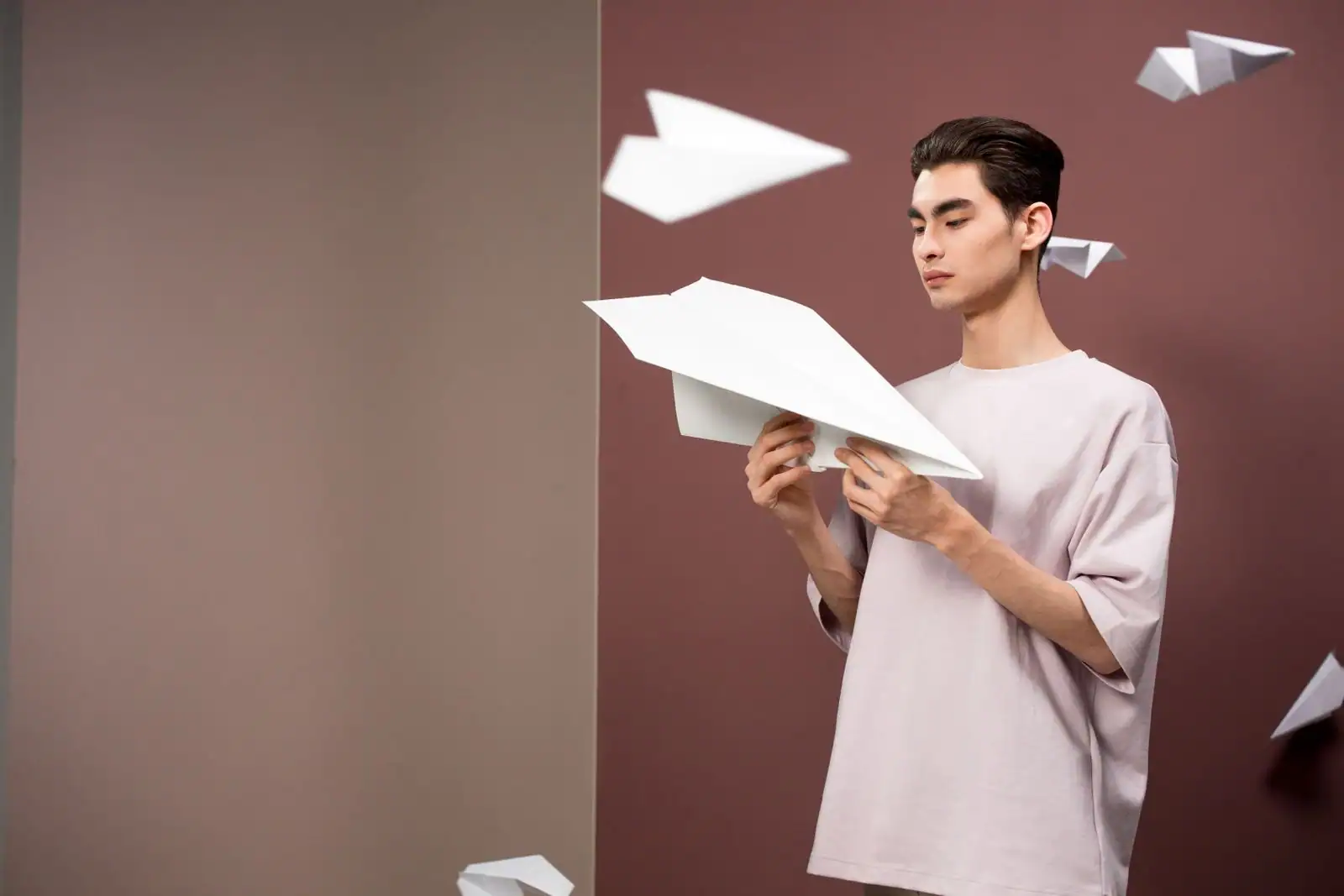 Homme tenant un avion en papier en forme de fléchette, d'autres avions volant autour