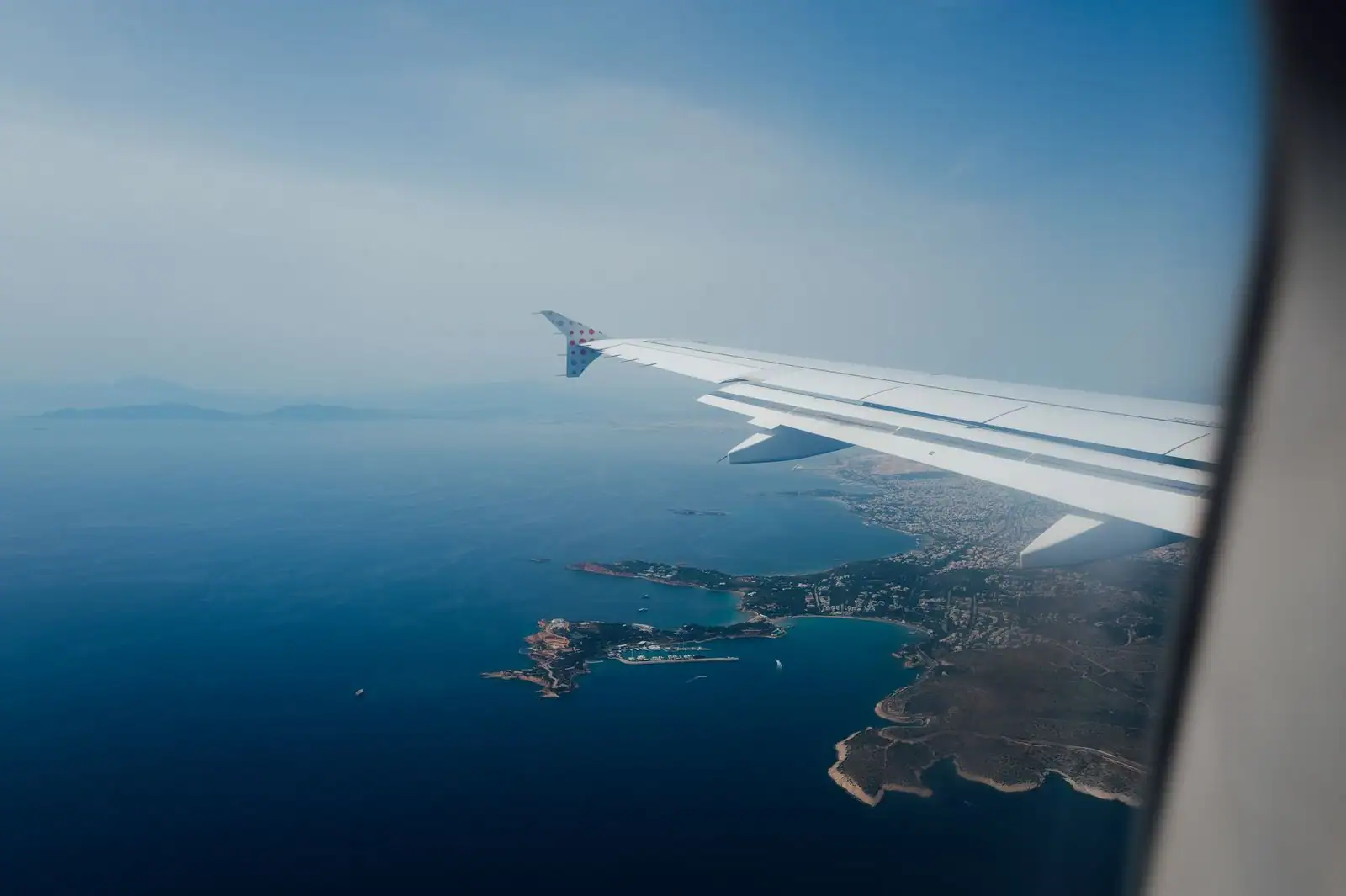 Aile d'avion au-dessus du littoral et de la mer, vue depuis le hublot