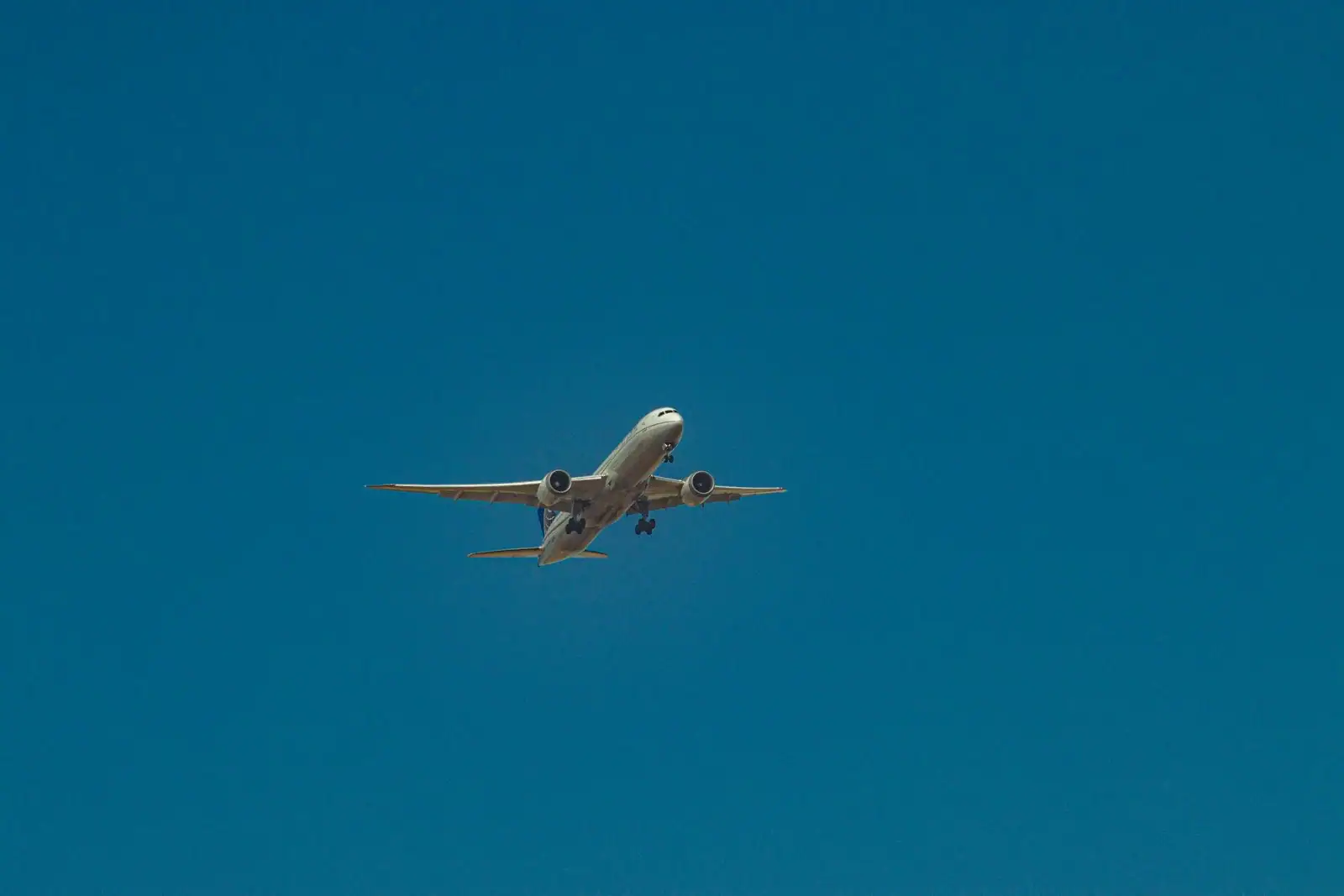 Avion de ligne en vol, train d'atterrissage sorti, vu d'en bas dans un ciel bleu profond