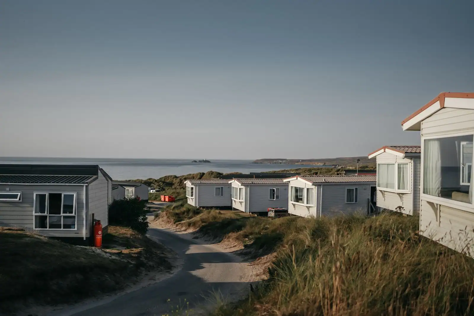 Rangées de mobil-homes dans un camping de bord de mer, installées sur des dunes face à la mer