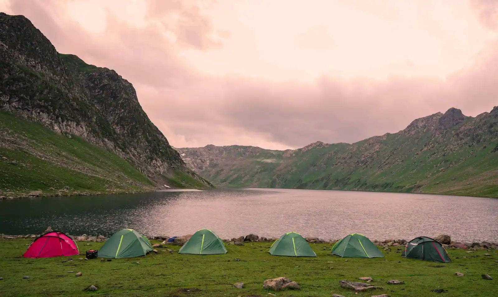 Tentes de camping installées sur une pelouse au bord d'un lac de montagne