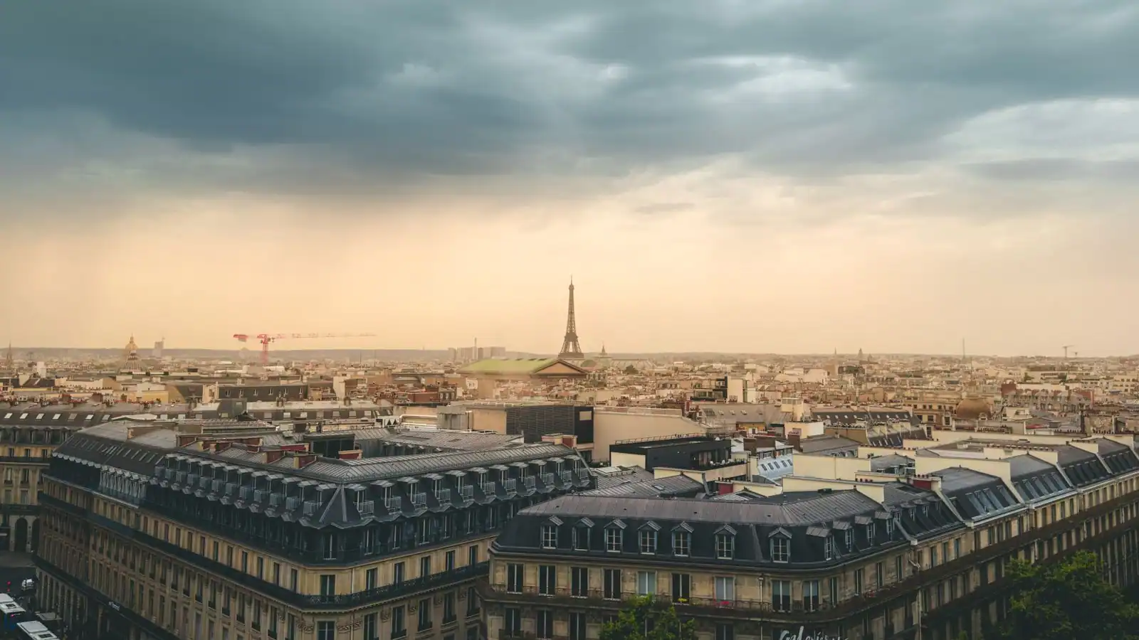 Vue sur les toits de Paris avec la tour Eiffel se détachant à l'horizon en fin de journée.