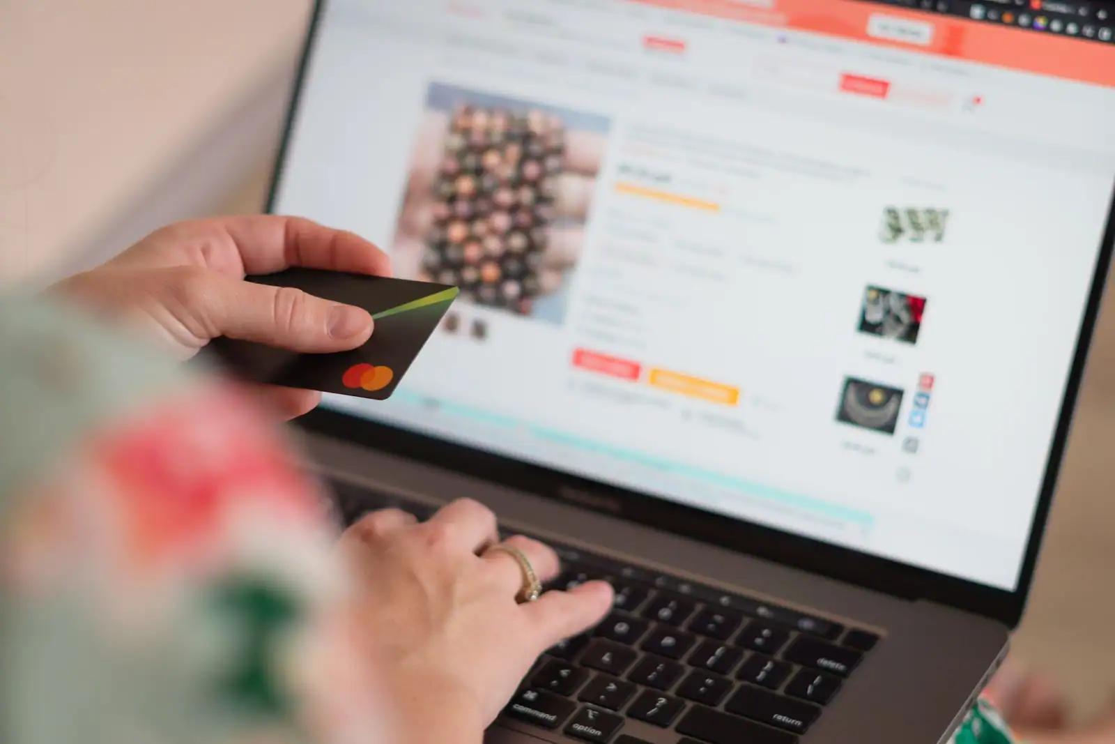 Personne tenant une carte bancaire devant un ordinateur portable affichant une boutique en ligne.