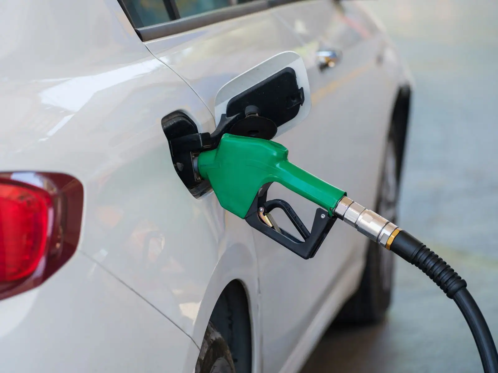 Pistolet de pompe à carburant inséré dans le réservoir d'une voiture en station-service.