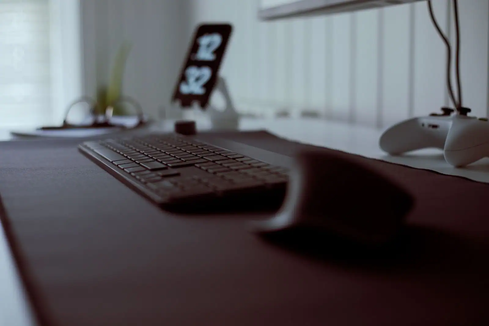 Bureau de jeu avec un clavier d'ordinateur et une manette de console posés sur un tapis sombre.