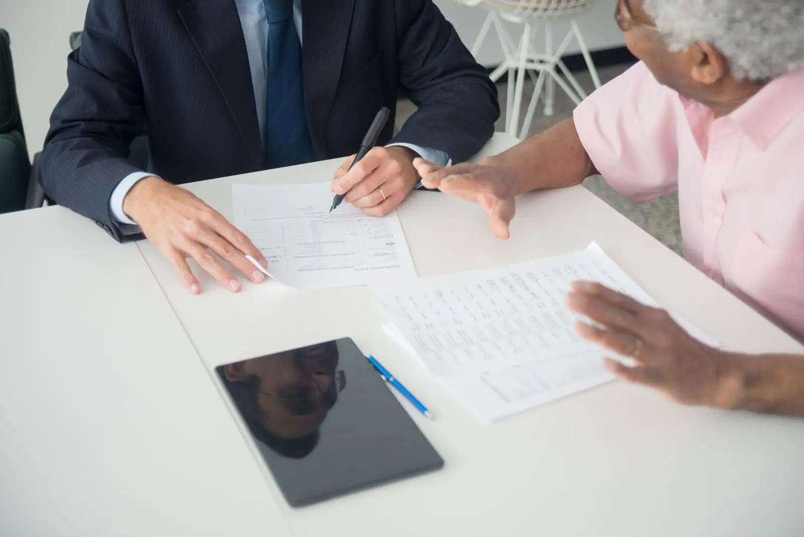Deux personnes examinent des documents d'assurance autour d'une table lors d'un rendez-vous de conseil.