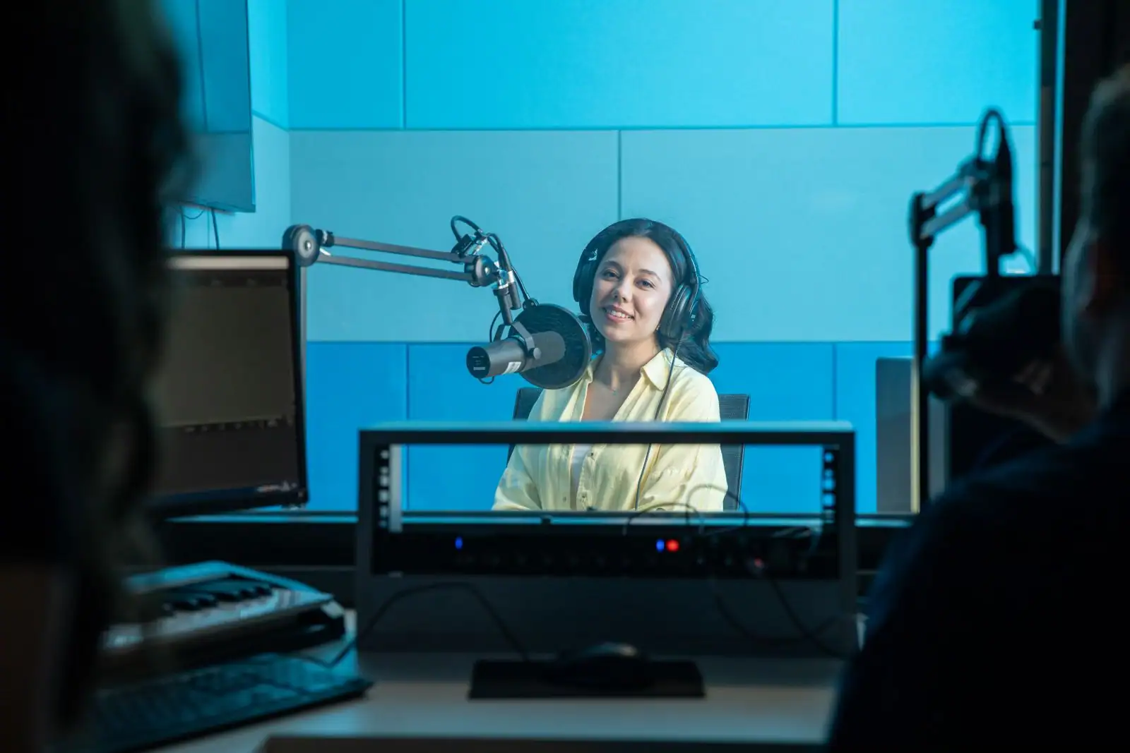 Animatrice avec un casque devant un micro dans un studio de radio aux panneaux acoustiques