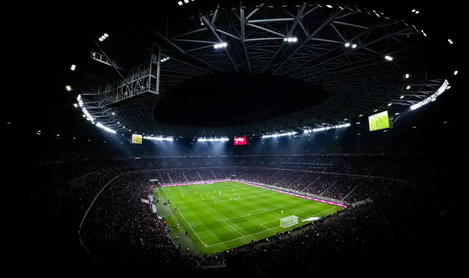 Stade de football illuminé et rempli de spectateurs un soir de match
