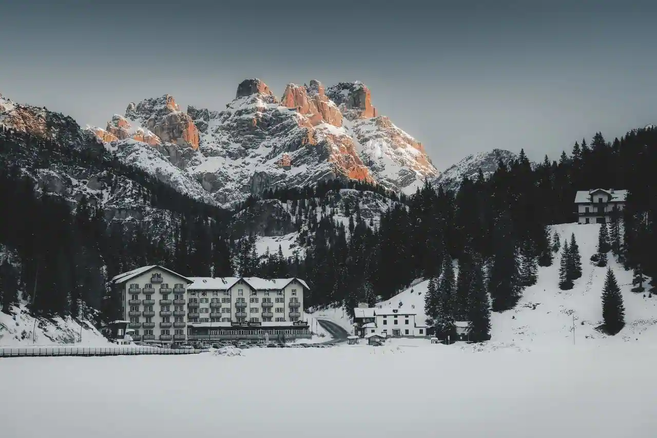 Sommets enneigés des Dolomites dominant un hôtel de montagne au bord d'un lac gelé en hiver