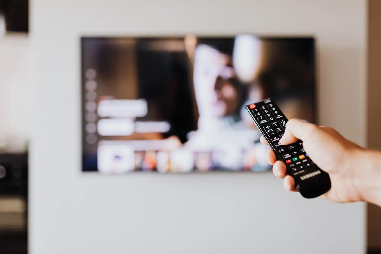 Une télécommande pointée vers un téléviseur affichant une plateforme de streaming dans un salon.