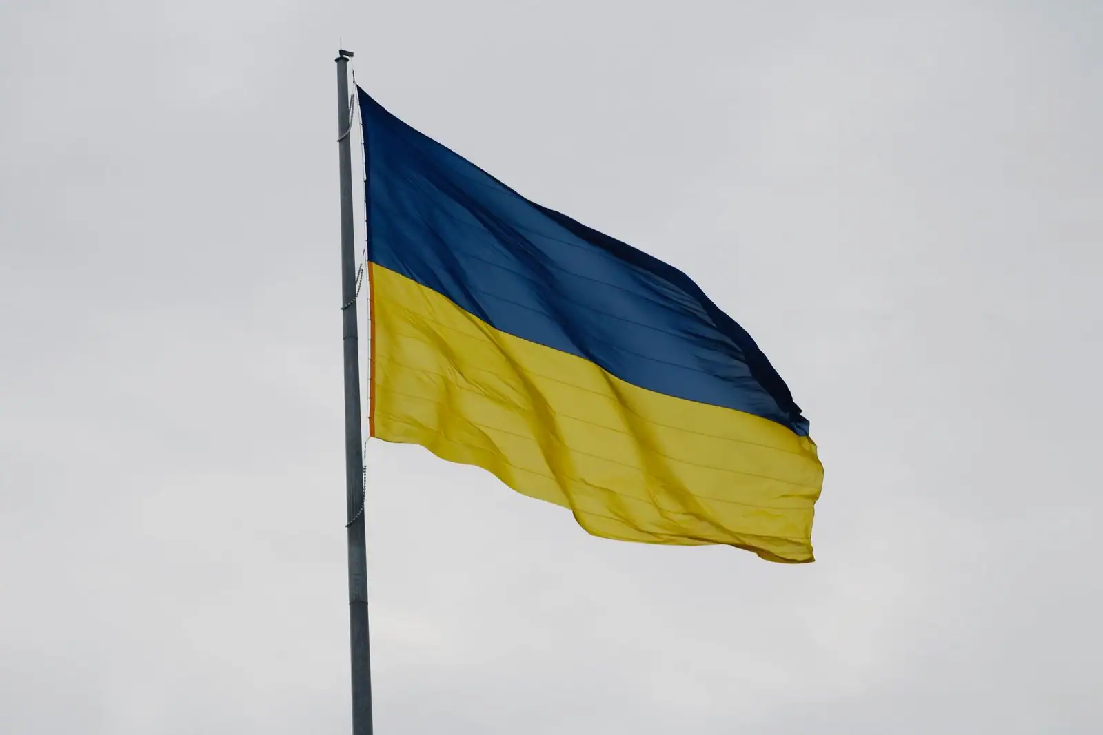 Drapeau national ukrainien, bleu et jaune, flottant sur un mât contre un ciel gris couvert