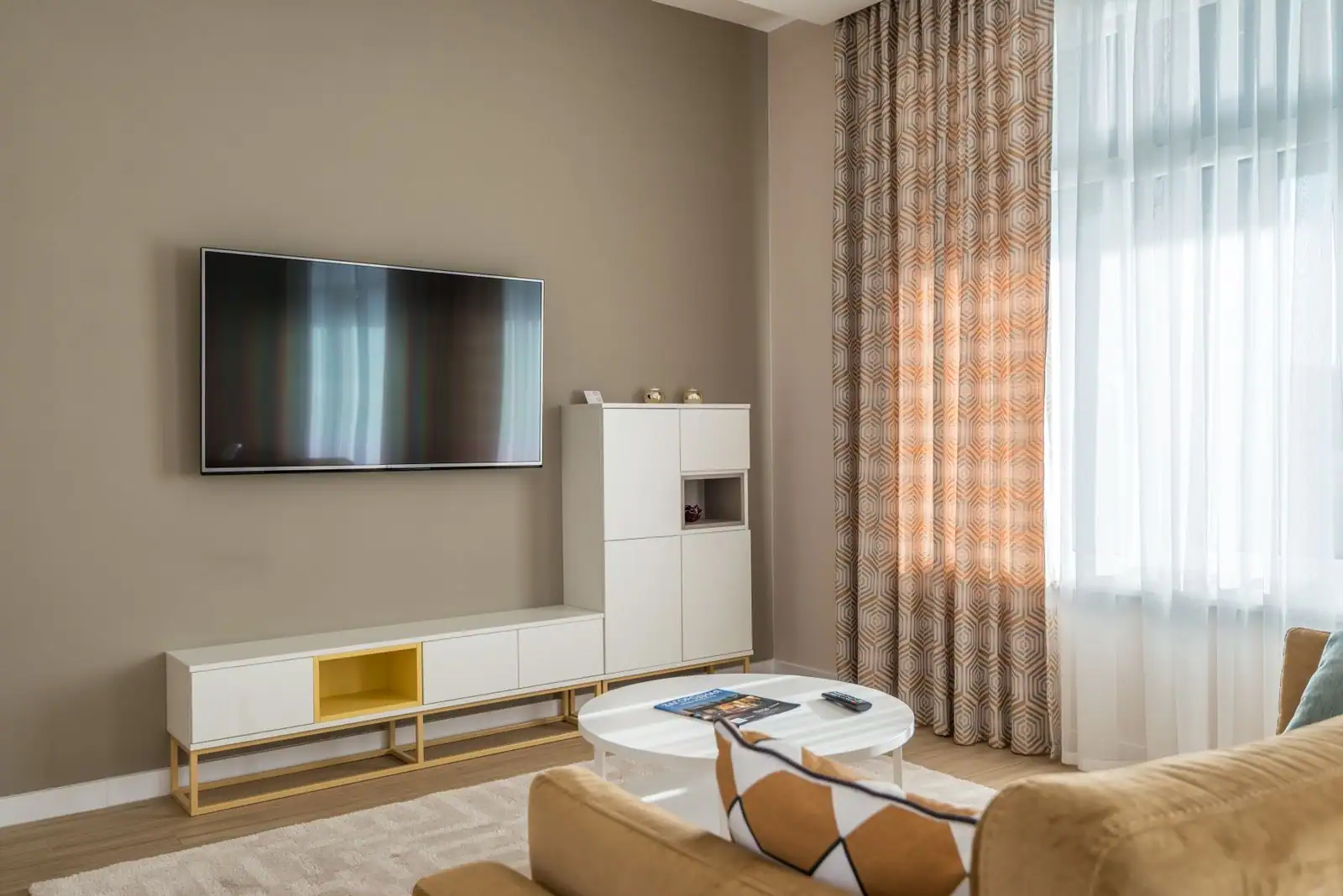 Téléviseur à écran plat fixé au mur d'un salon moderne, face à un canapé et une table basse.