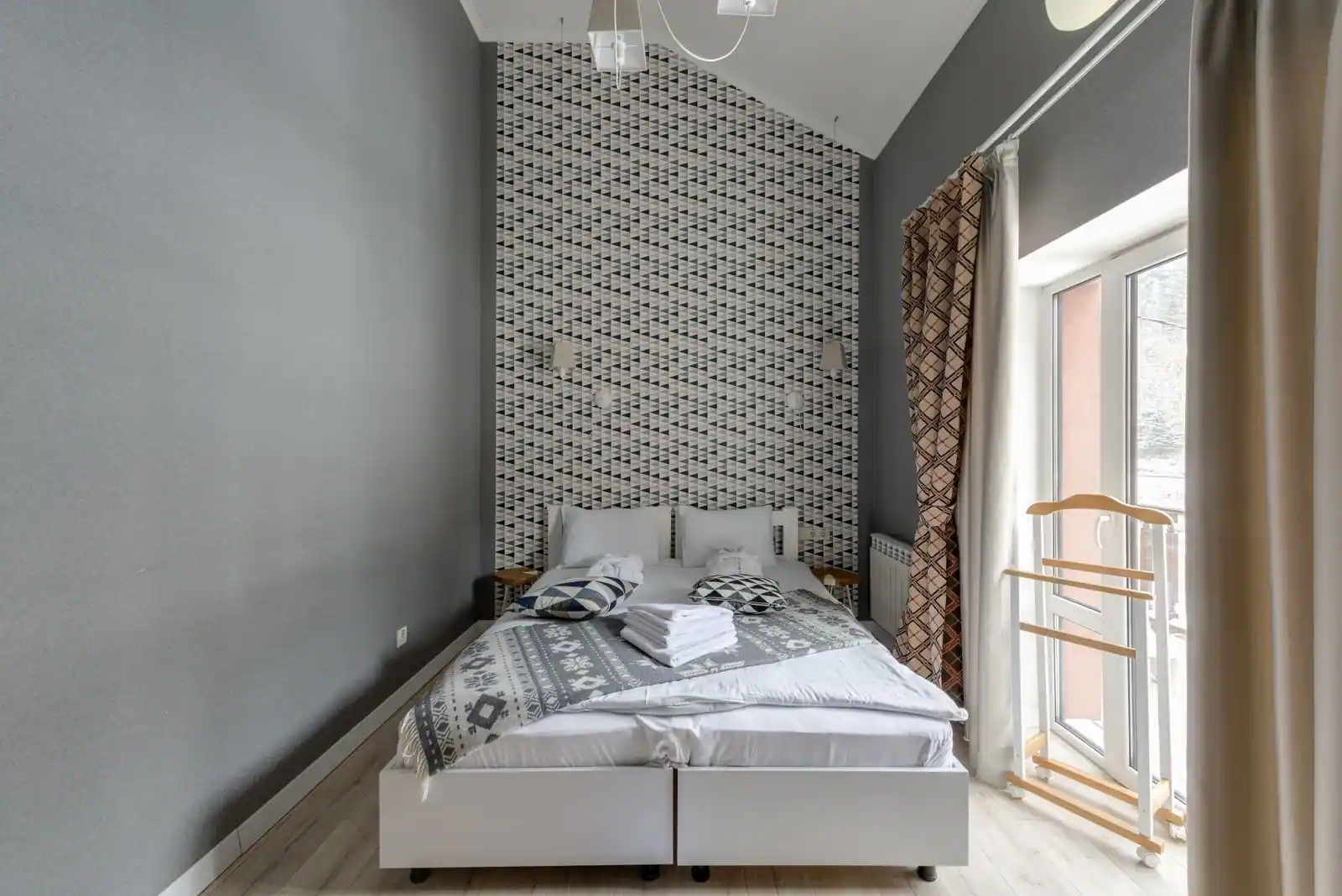 Une chambre d'hôtel moderne et fonctionnelle avec un lit double et une grande fenêtre lumineuse.