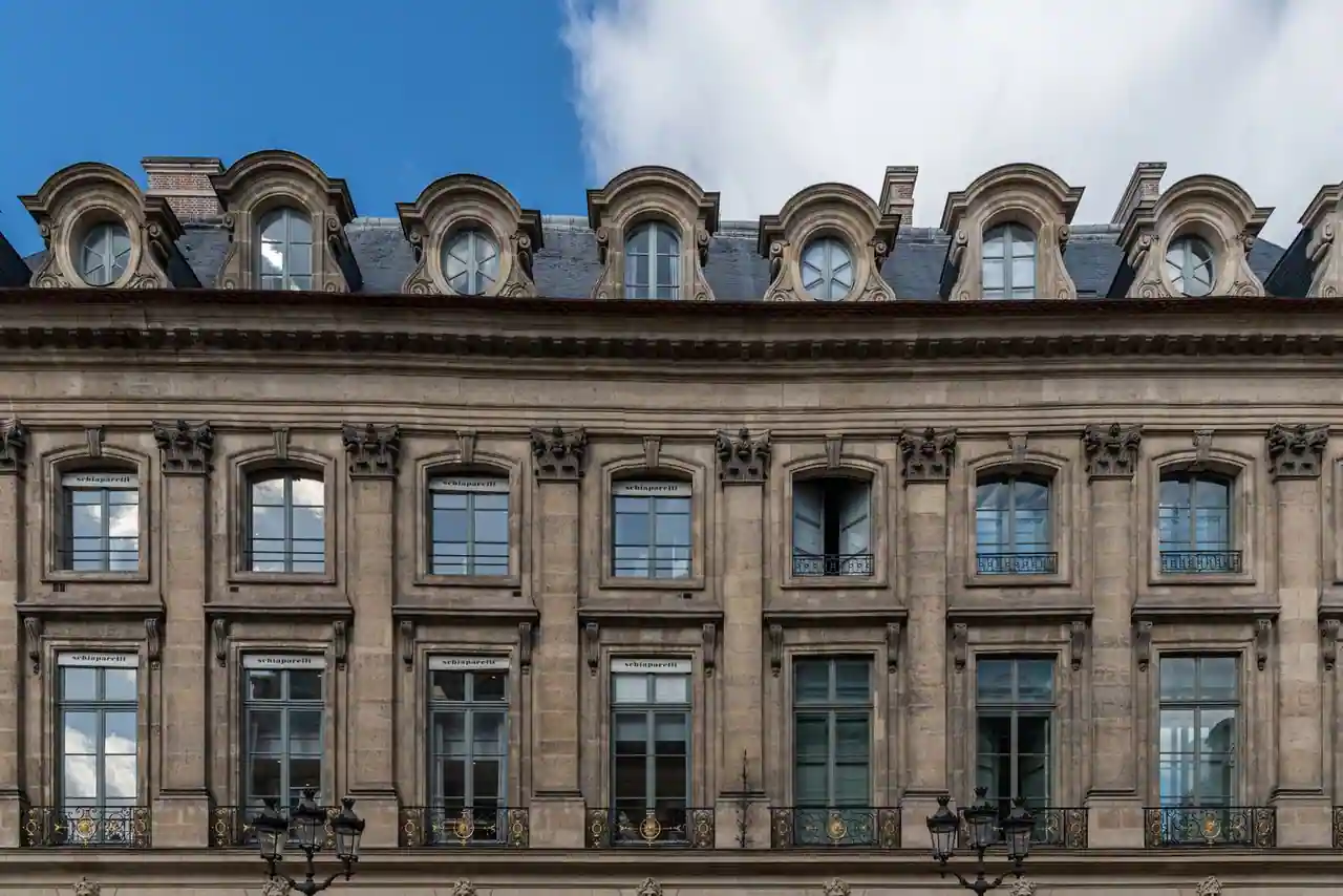 Façade classique en pierre d'un hôtel particulier parisien, avec ses hautes fenêtres et ses lucarnes.