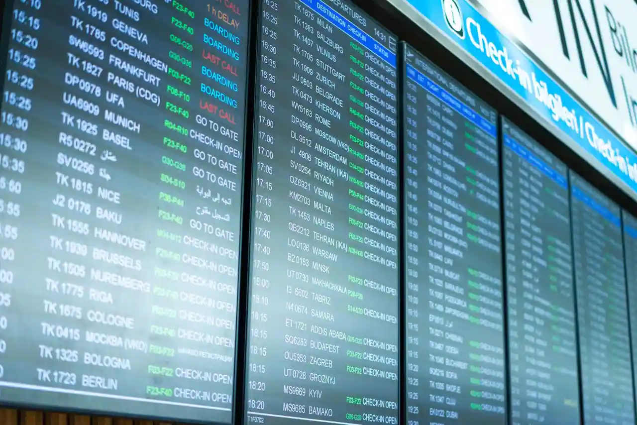Panneau d'affichage des départs dans un aéroport, avec destinations de vols et statuts d'embarquement