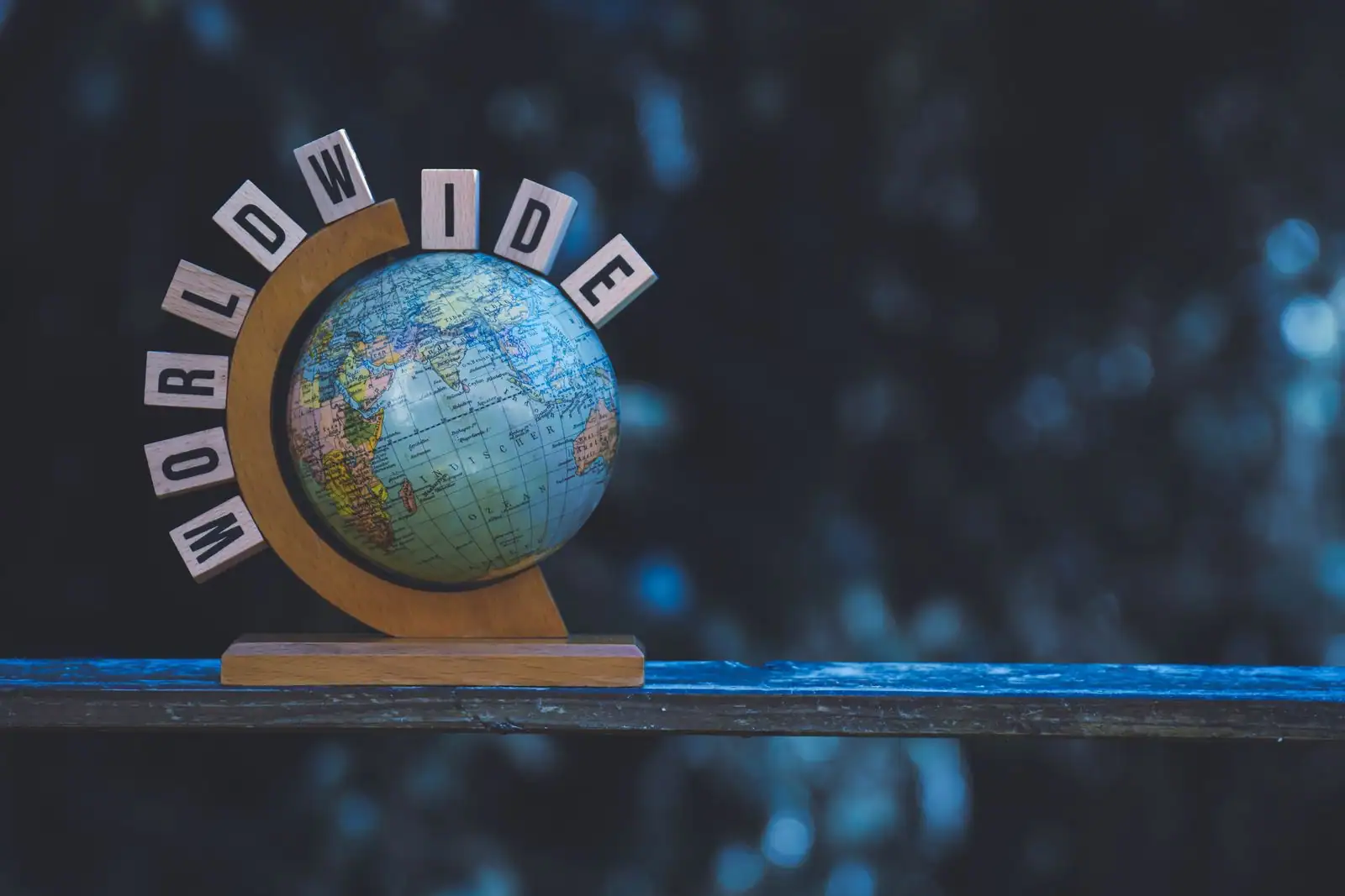 Un petit globe terrestre sur un socle en bois, entouré de lettres en bois formant le mot « worldwide ».