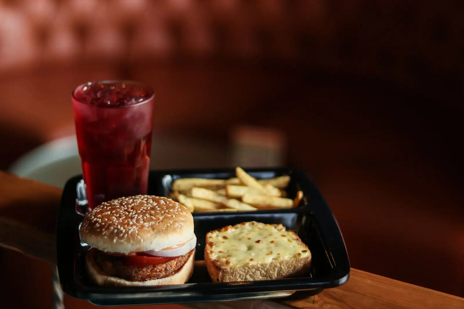 Menu de restauration rapide avec burger, frites et boisson posé sur un plateau en libre-service