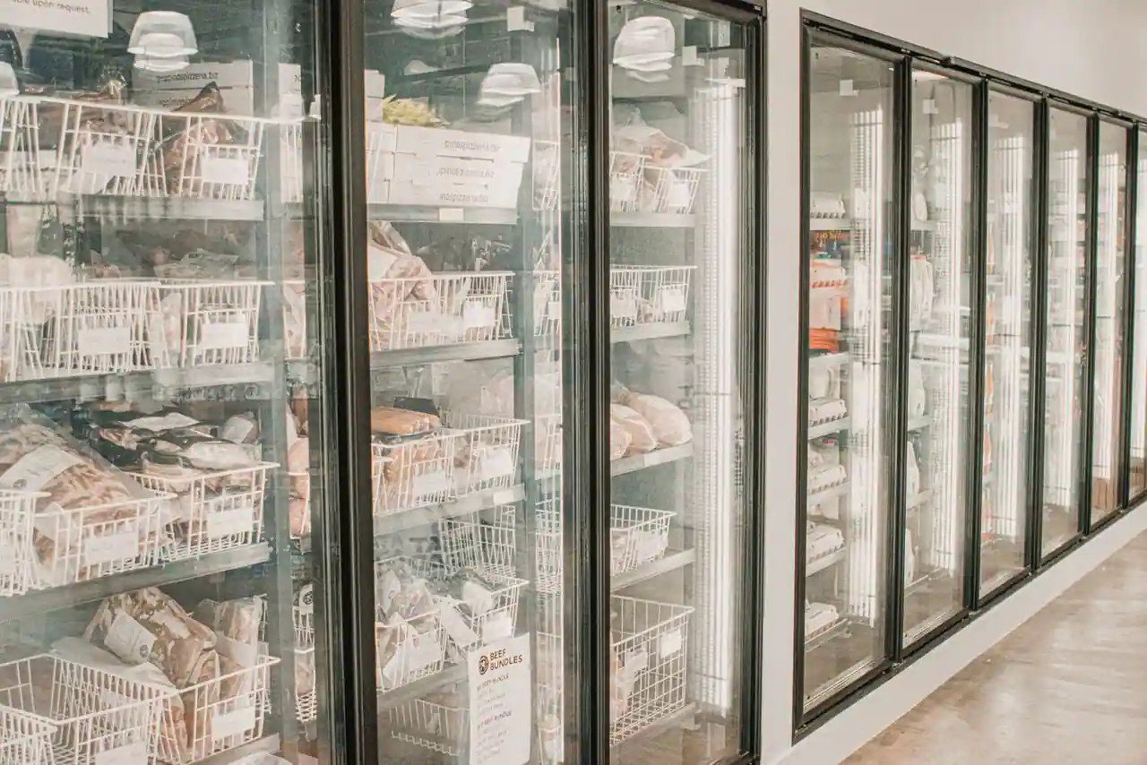 Rangée de congélateurs à portes vitrées garnis de produits surgelés dans un magasin