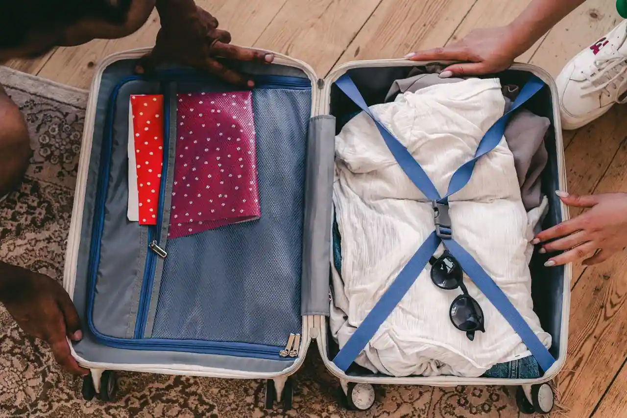 Valise ouverte remplie de vêtements et de lunettes de soleil, préparée pour un départ en vacances