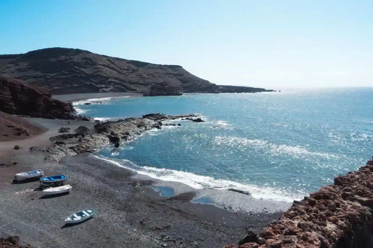 Plage de sable et côte volcanique baignées de soleil au bord de l'océan, ambiance des îles Canaries