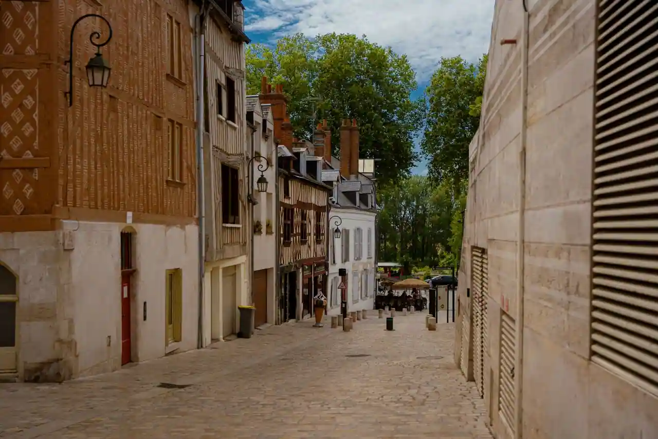 Ruelle pavée d'une vieille ville européenne bordée de façades anciennes sous le soleil