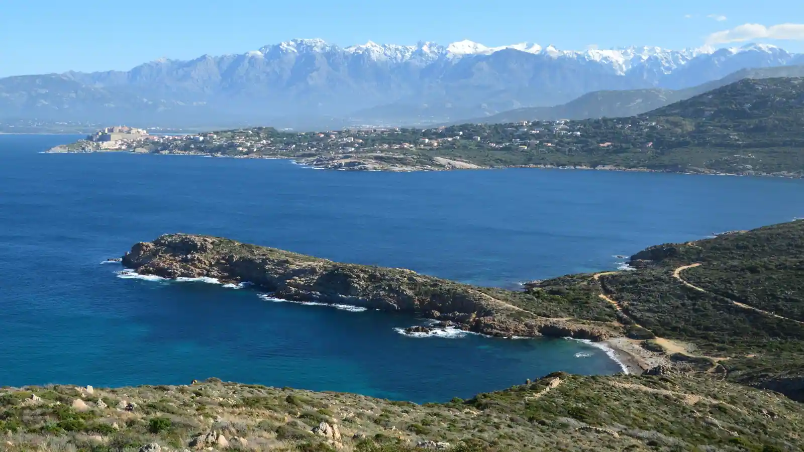 Le golfe de Calvi et sa citadelle, en Corse, devant les montagnes enneigées de l'intérieur de l'île.