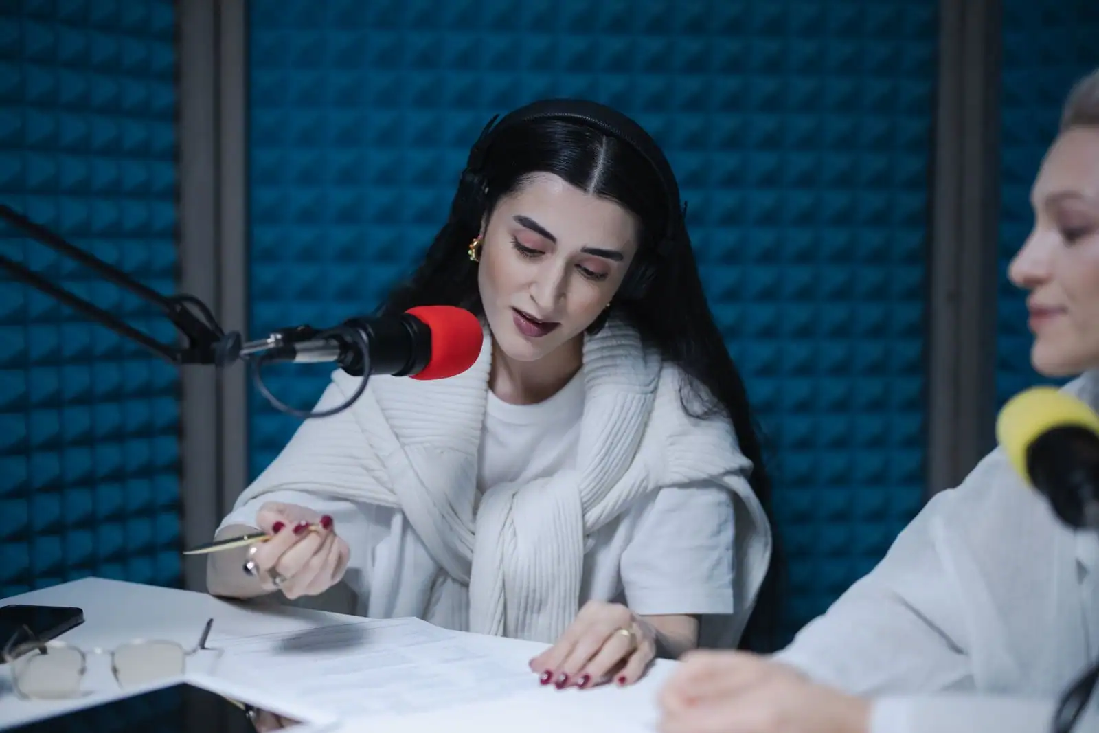 Animatrice casquée penchée vers un micro de studio, ses notes posées devant elle, pendant une émission de radio