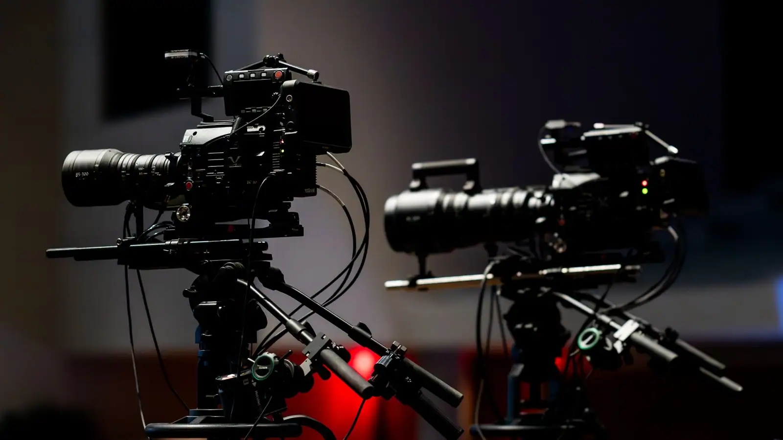 Deux caméras de studio installées sur pied dans un plateau de télévision faiblement éclairé, prêtes à tourner.