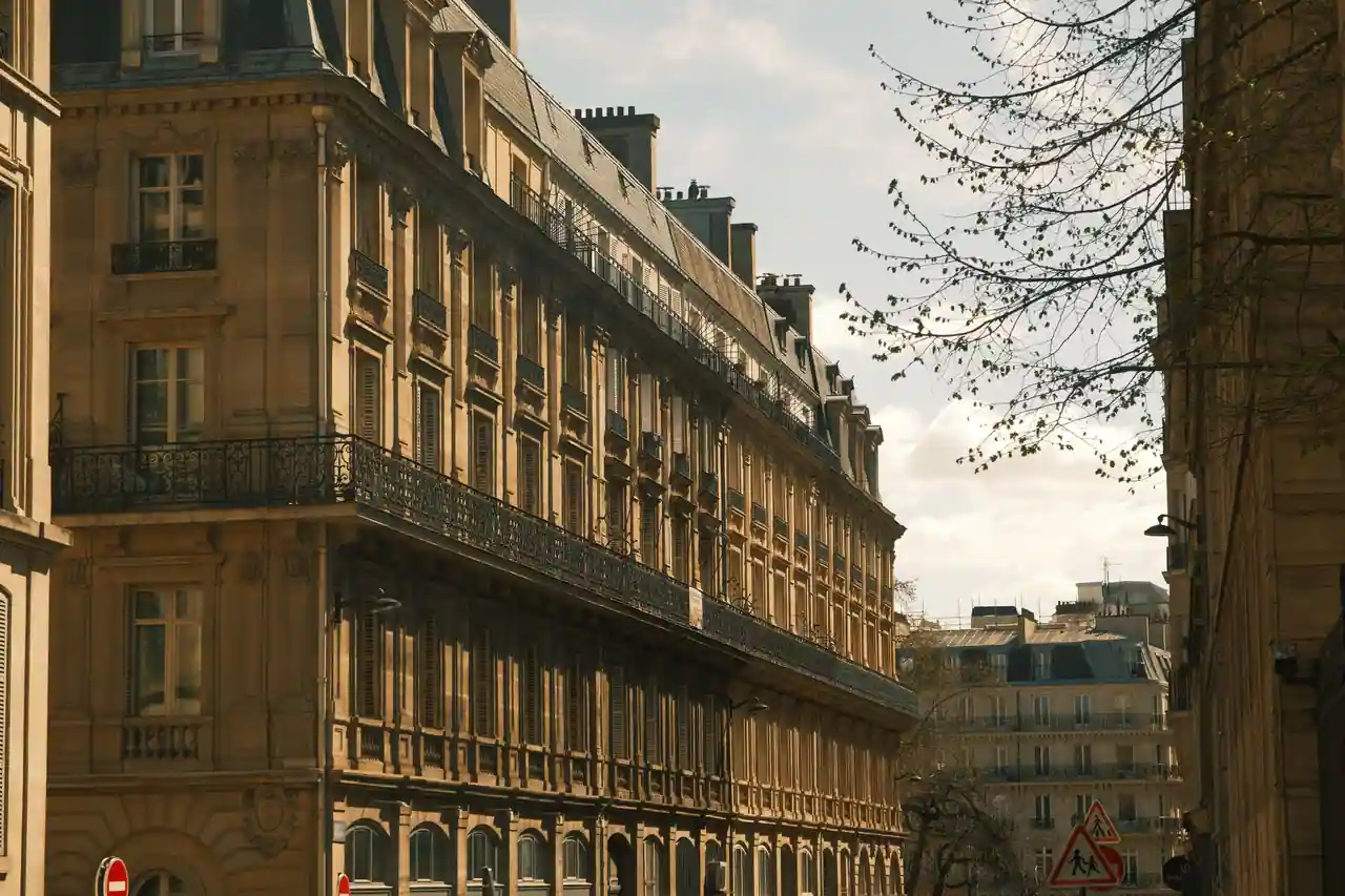 Longue façade haussmannienne parisienne aux balcons de fer forgé, dans la lumière de fin de journée.