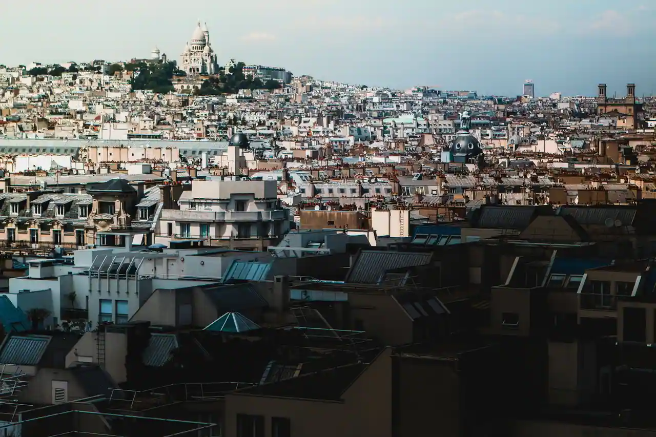 Toits parisiens vus depuis les hauteurs, avec le dôme du Sacré-Cœur dominant le quartier de Montmartre.