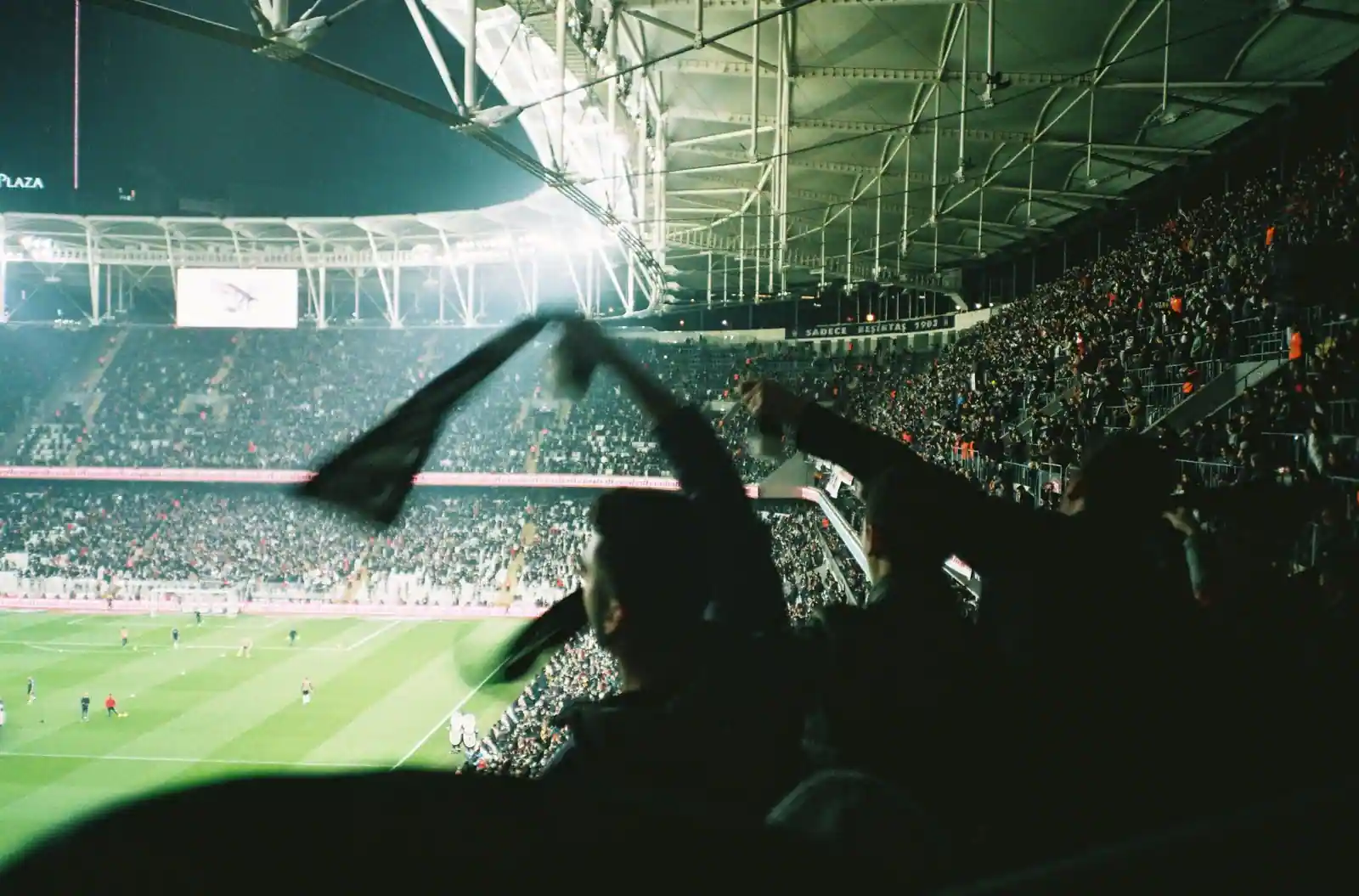 Tribunes pleines et écharpes levées lors d'un match en soirée au stade de Beşiktaş, à Istanbul.