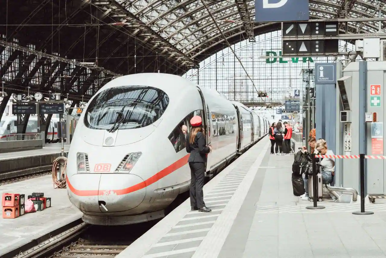 Rame à grande vitesse à quai sous la verrière d'une gare allemande, voyageurs et bagages sur le quai