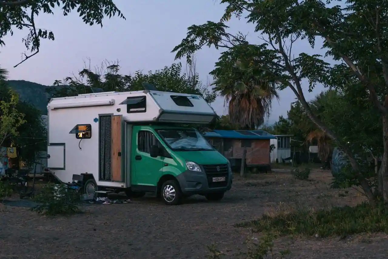 Rangée de mobil-homes et piscine dans un camping du littoral français, entourés de pins