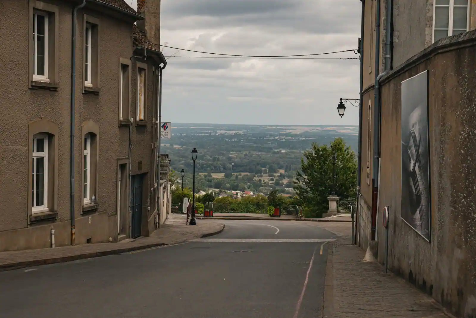Rue en pente d'un village perché du Val de Loire, avec une vue dégagée sur la vallée et la campagne environnante.