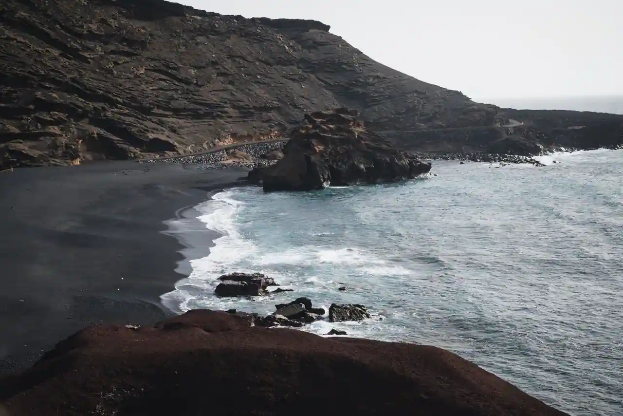 Une plage de sable noir volcanique borde l'océan sur une île des Canaries, en Espagne.