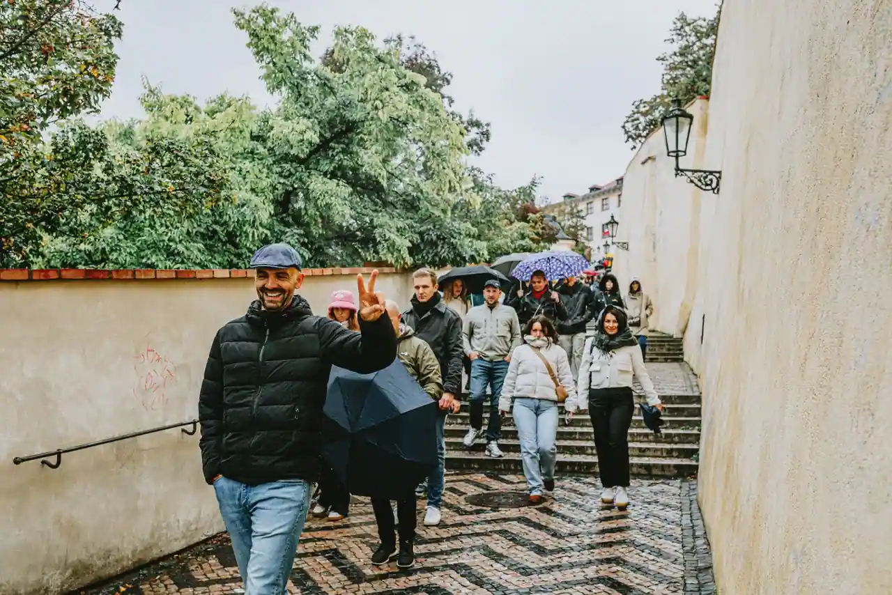 Groupe de touristes marchant sous la pluie dans une rue pavée d'une ville historique européenne